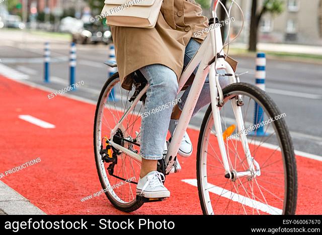woman riding bicycle along red bike lane in city