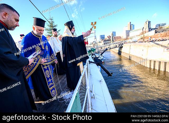 08 January 2023, Hamburg: Auxiliary Bishop Bartholomaios Kessidis of Arianz (M) holds a cross over the Elbe during the ceremony