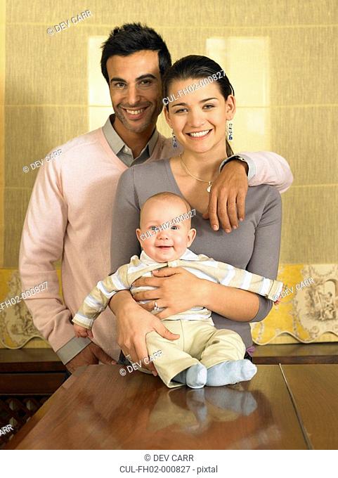 Young couple and baby son 1-3 months smiling, portrait