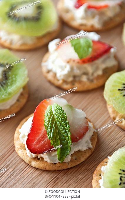 Crackers Topped with Cream Cheese, a Strawberry Slice and a Mint Leaf, Some Topped with Cream Cheese and Kiwi