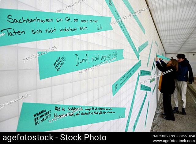 27 January 2023, Brandenburg, Oranienburg: Employees of the memorial place stick inscribed adhesive tapes on the wall in the interior of ""Station Z"" of the...