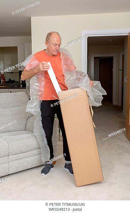 Man unpacking a brown cardboard box containing an excessive amount of protective air bags