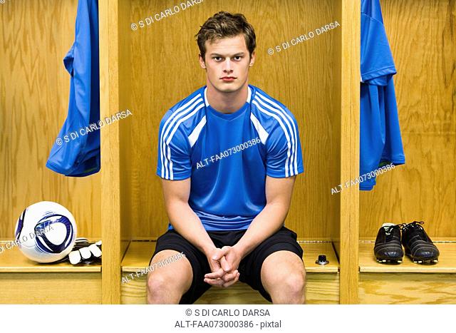 Young soccer player sitting in locker room, portrait