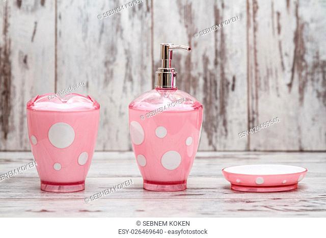 Set of cute pink bathroom accessories on white wooden background