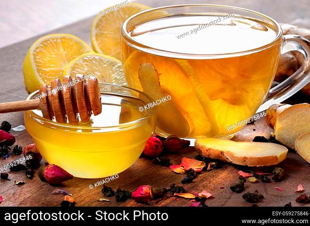 honey, lemon, ginger and a cup of tea with lemon on a wooden table. traditional cold remedies