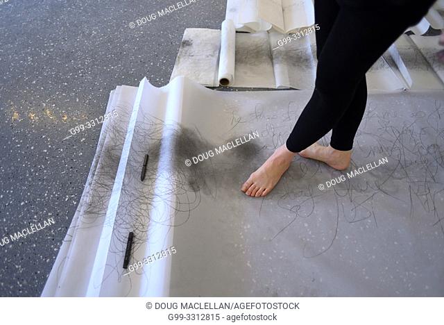 A woman artist aged 50 to 55 years old creates performance art that incorporates drawing, text, and walking