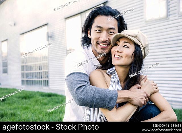 Korean couple hugging on lawn outside house
