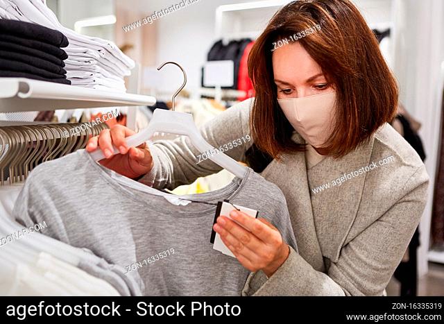 Kundin mit Maske wegen Covid-19 Pandemie beim Shopping in einer Boutique