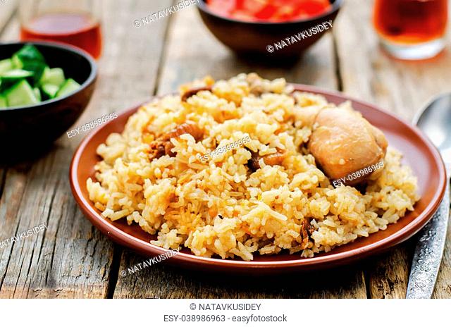 pilaf with dates, figs and chicken on a dark wood background. tinting. selective focus