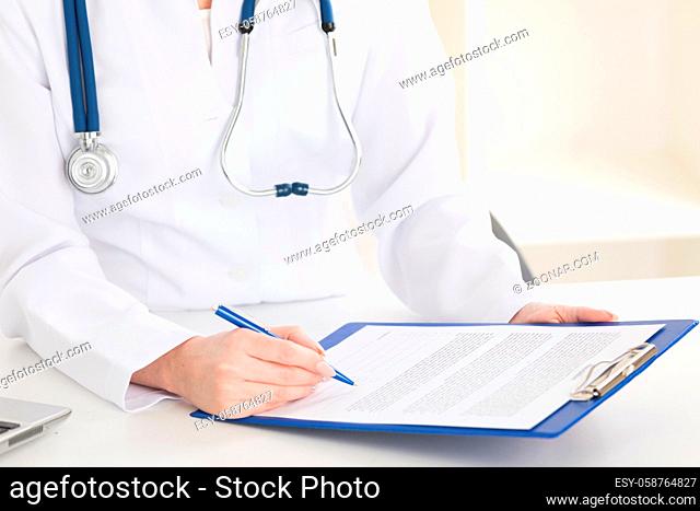 Female doctor hand hold silver pen filling patient history list at clipboard pad
