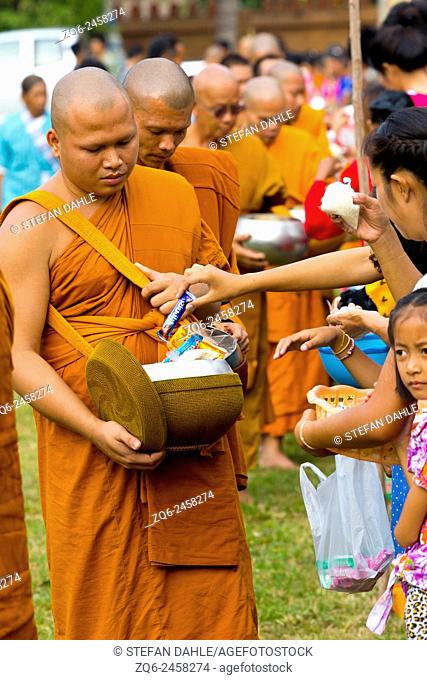 Monks collecting Alms during a traditional Procession in a rural Village in the Isaan Province, Thailand