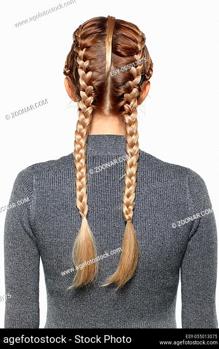 Back view portrait of beautiful young dark blonde woman. Female with creative braid hairdo on gray background