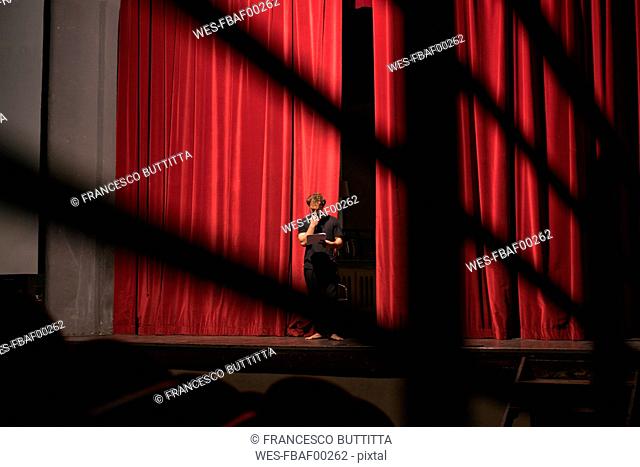 Barefoot actor standing on theatre stage studing the script