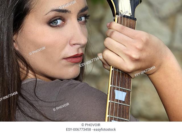 Woman holding her electric guitar behind her back