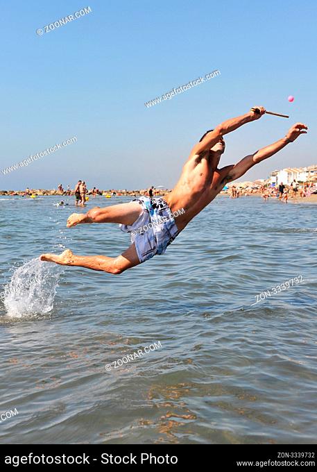 young man playing beach tennis in the sea