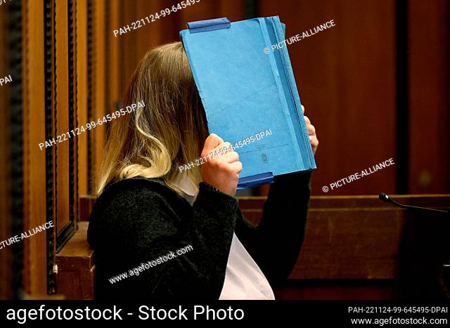 24 November 2022, North Rhine-Westphalia, Mönchengladbach: The defendant covers her face with a blue folder in the regional court