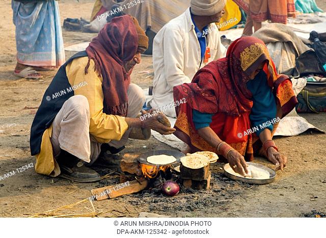 Couple cooking food in Kumbh mela ; Allahabad ; Uttar Pradesh ; India