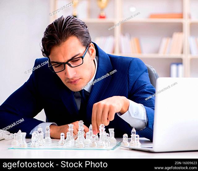 The young businessman playing glass chess in office