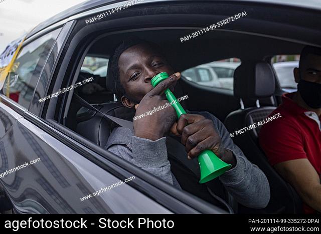 14 November 2020, Spain, Telde: A participant sits in a car and blows a horn. People demonstrated for the rights of migrants in Gran Canaria with a motorcade...