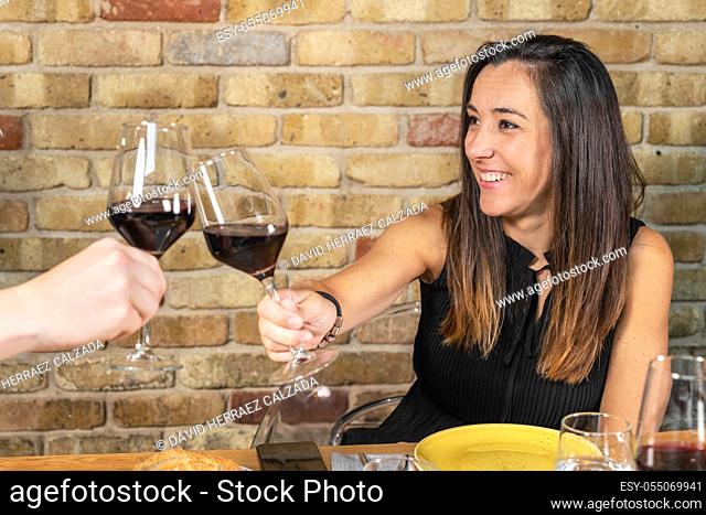 Close up of young couple toasting with glasses of red wine at restaurant. High quality photo
