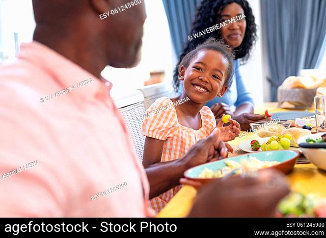 African american smiling cute girl having lunch with family at home on thanksgiving day