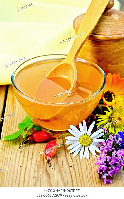 Honey with flowers and spoon on board