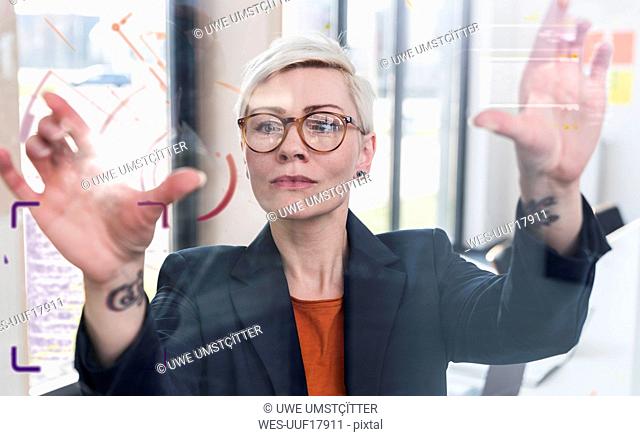 Businesswoman touching glass wall with data in office