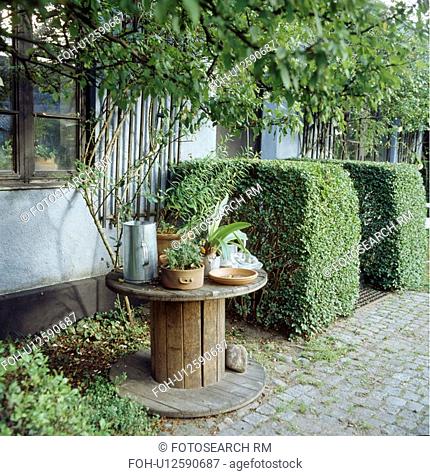 Old wooden table and clipped shrubs in country garden