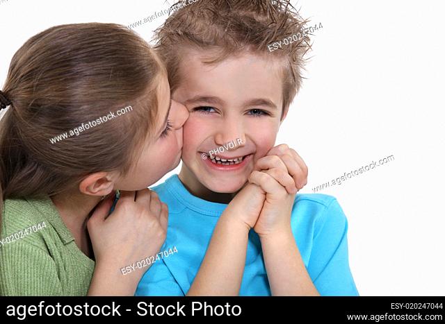 Playful little boy being kissed by a little girl