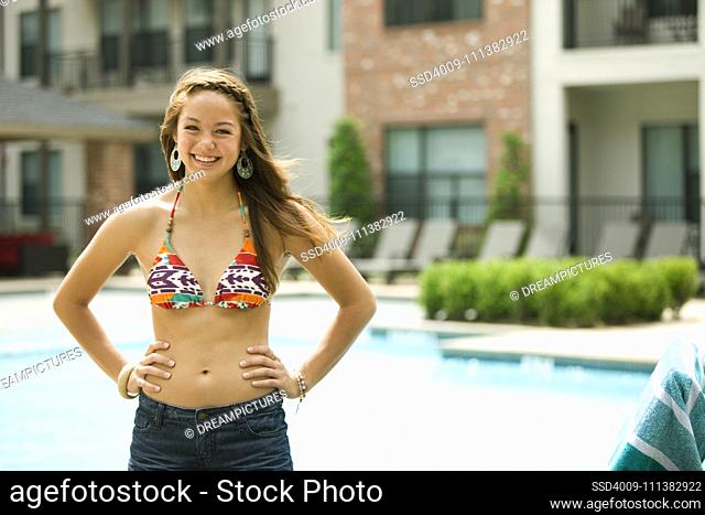 Mixed race girl wearing bikini standing near swimming pool