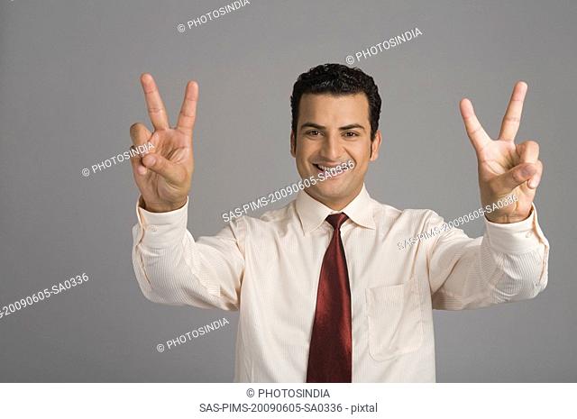 Portrait of a businessman showing victory sign