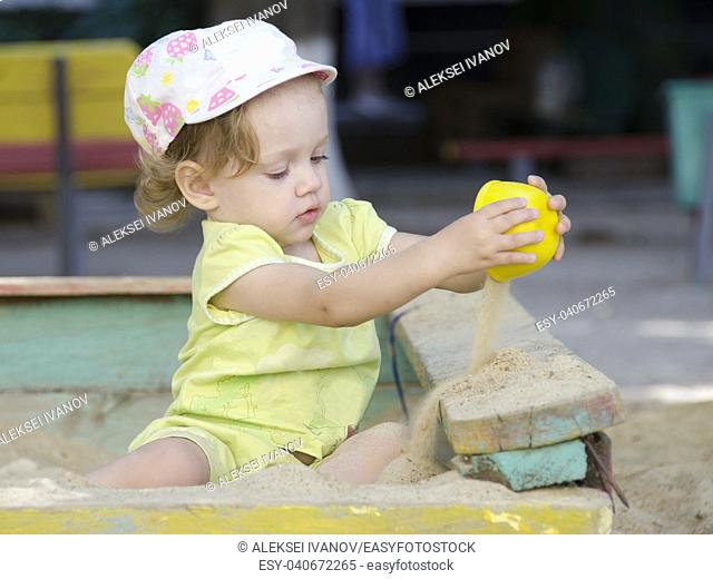 A girl is pouring sand in a sandbox