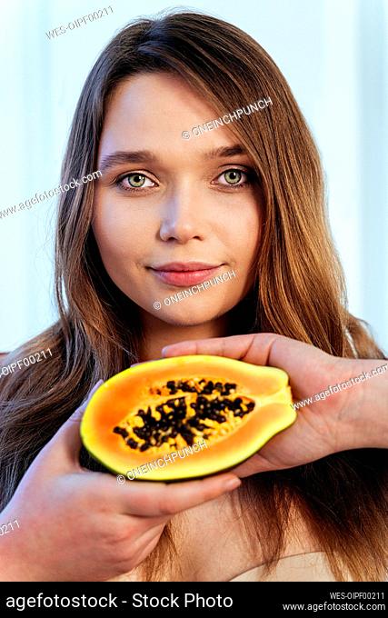 Beautiful female model with green eyes holding slice of papaya