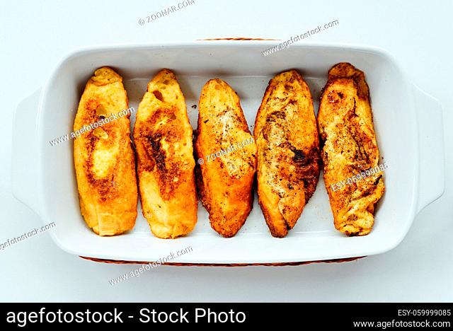 Torrijas, typical Spanish sweet fried toasts of sliced bread soaked in eggs and milk on tray isolated on white background