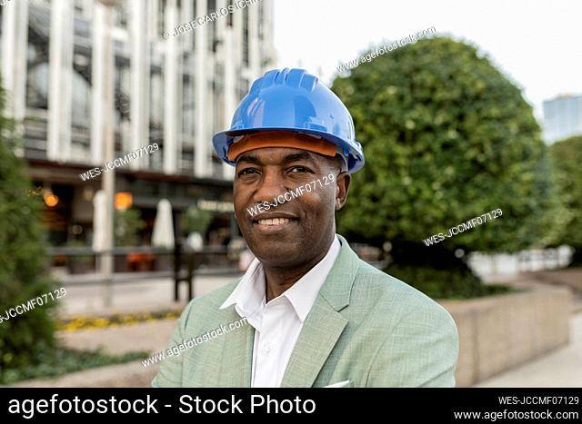 Smiling engineer wearing hardhat in front of building