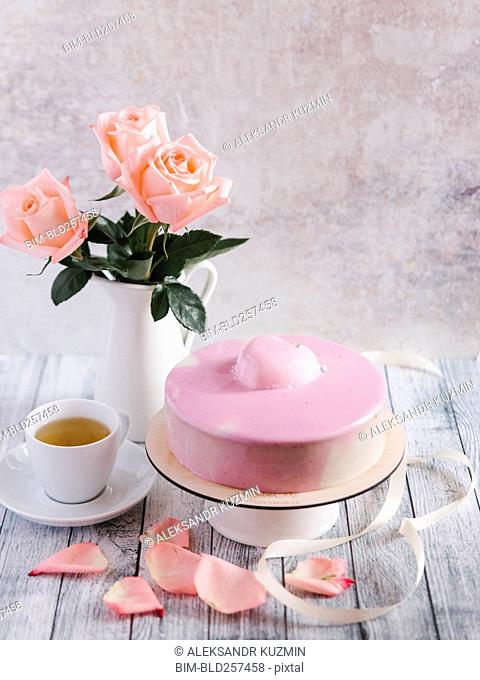 Pastel rosa con té cerca del jarrón de flores