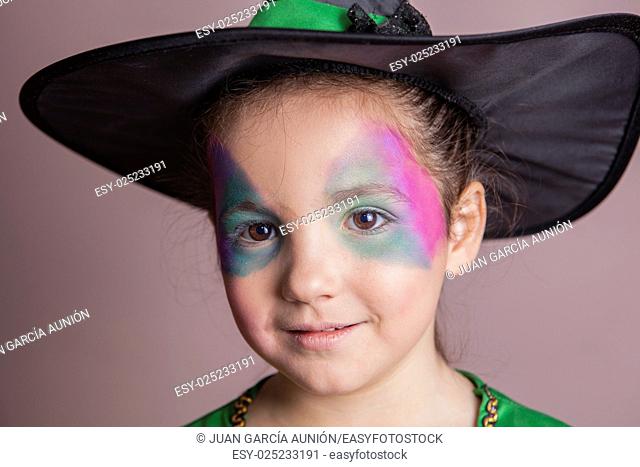 Little cute girl made up and costumed as a witch before halloween party. She is smiling