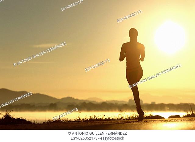 Runner woman silhouette running at sunset with the sun in the background