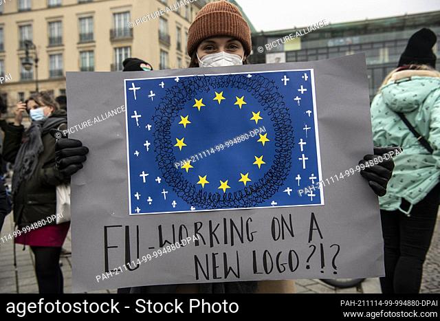 14 November 2021, Berlin: ""EU - working on a new logo?!?"" is written on a poster at a demonstration for the immediate admission of migrants at the...