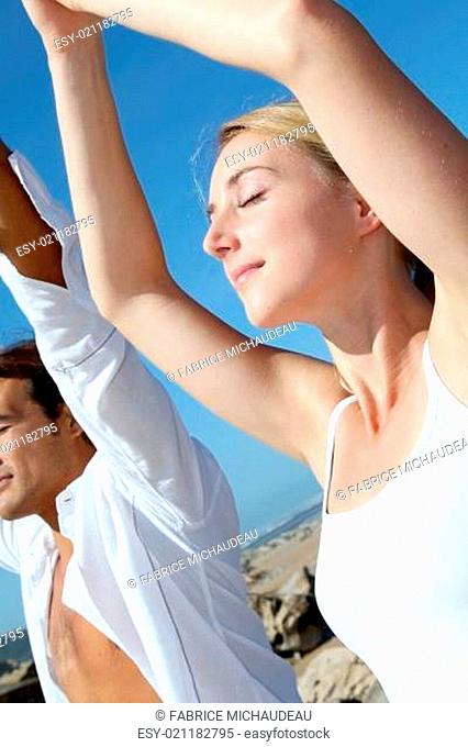 Couple doing yoga exercises on the beach