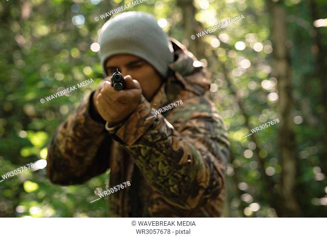 Hunter shooting with rifle in forest
