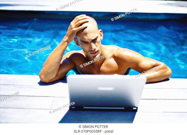 Man using laptop in swimming pool
