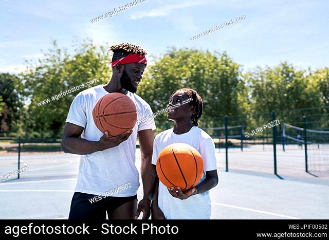 Father and son with basketball on basketball court