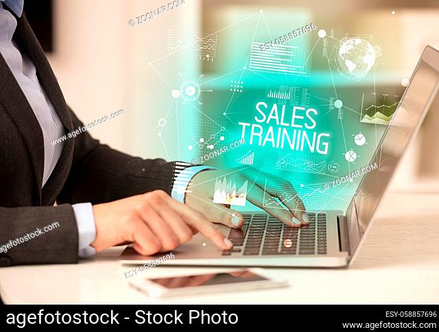 Side view of a business person working on laptop with SALES TRAINING inscription, modern business concept