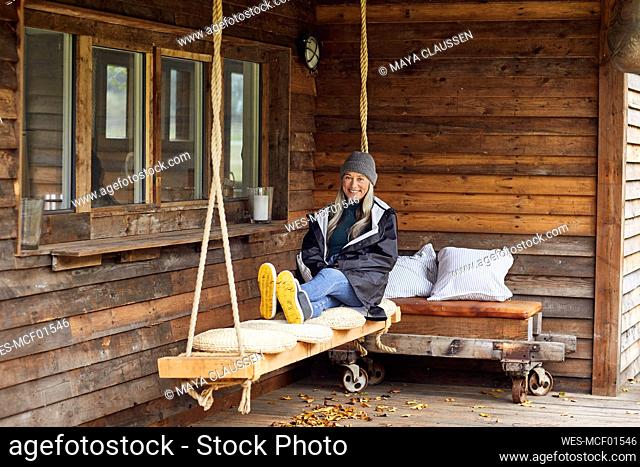 Happy mature woman relaxing on swing at patio in back yard