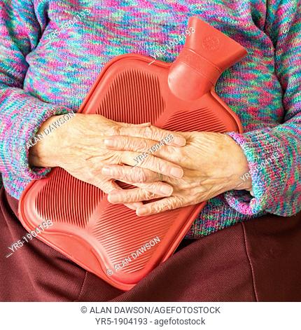 Elderly lady kkeping warm in winter with hot water bottle  England, United Kingdom