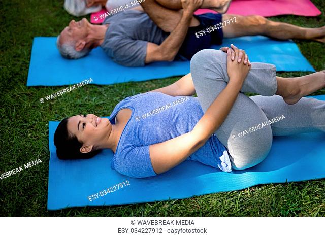 Smiling trainer exercising while lying down with senior people