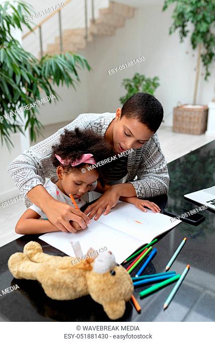 Mother helping her daughter with her homework on a table