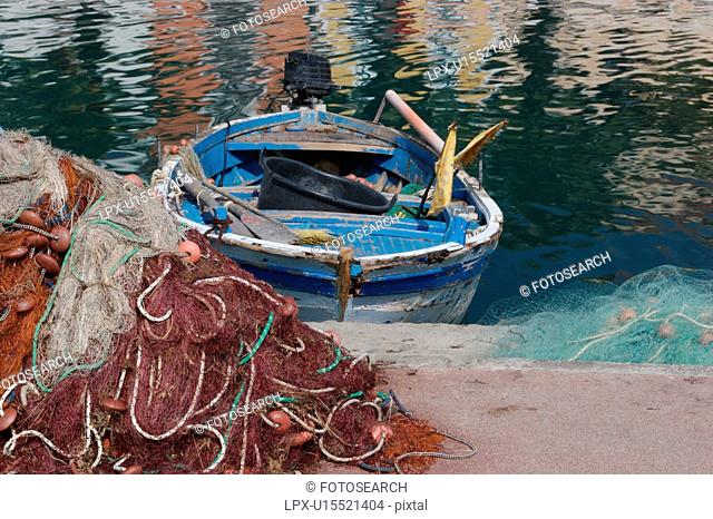 Scario harbour with old fishing boat moored, fishing nets on quayside, on sunny, summer morning