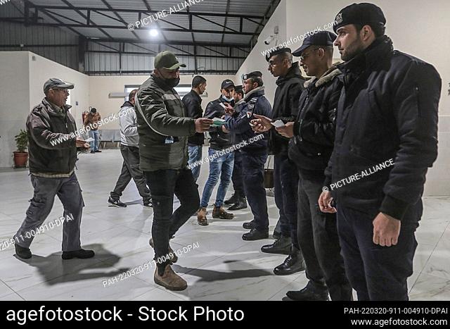 20 March 2022, Palestinian Territories, Beit Hanoun: Police officers check the papers of Palestinian workers at the Erez crossing as they leave Beit Hanoun in...